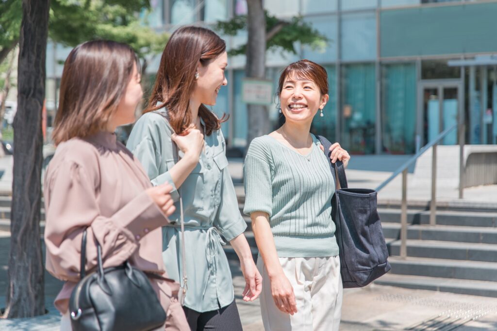 屋外で笑顔で話す３人の女性