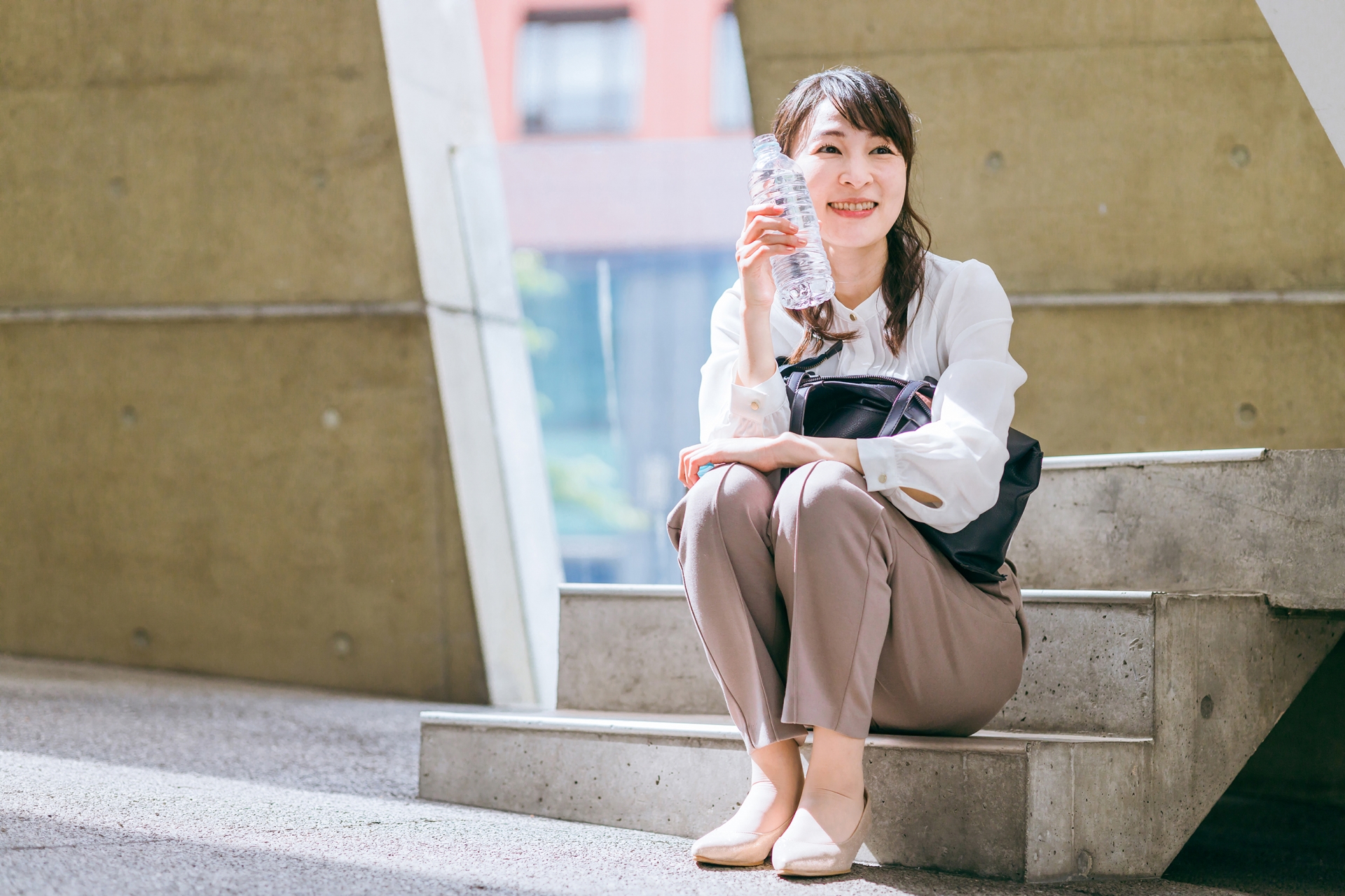 階段に座って水分補給の休憩をする女性