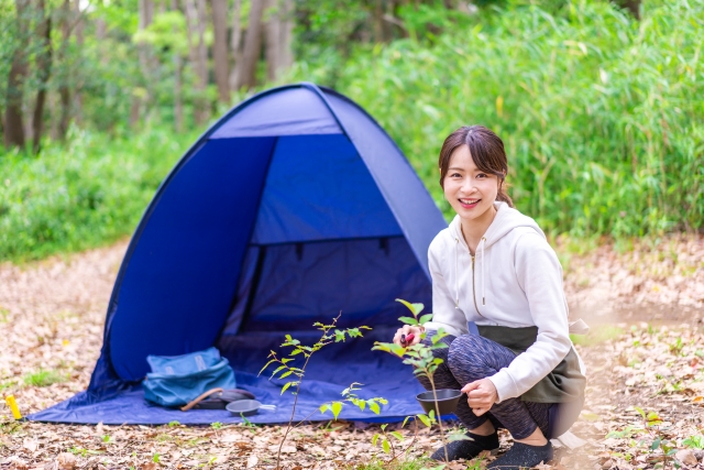 青いテントと横に座る笑顔の女性