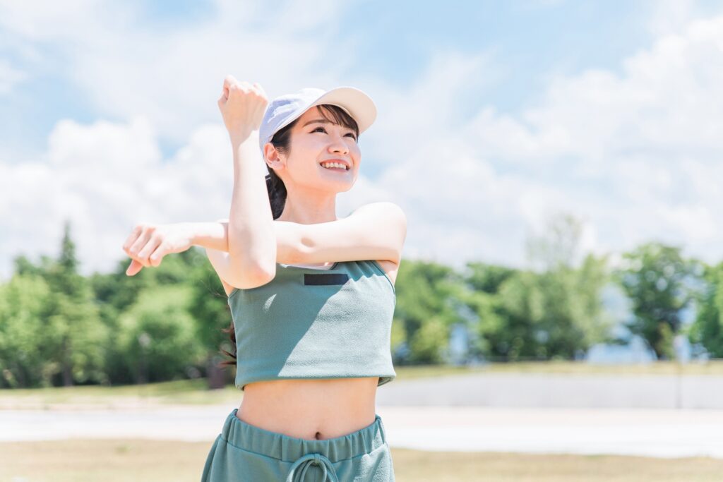 屋外でストレッチする白い帽子の女性