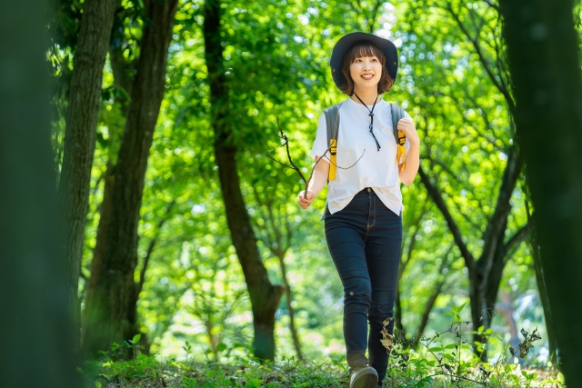 山道をハイキングする帽子をかぶった女性