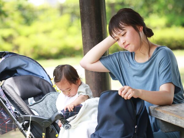 ベビーカーの赤ちゃんと疲れた様子のママ