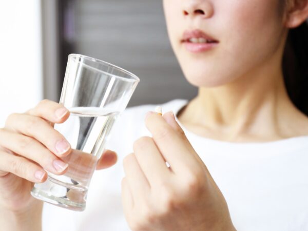 コップで薬を飲む様子