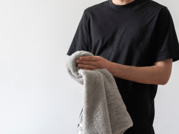 タオルで右腕を拭いている黒いTシャツの男性