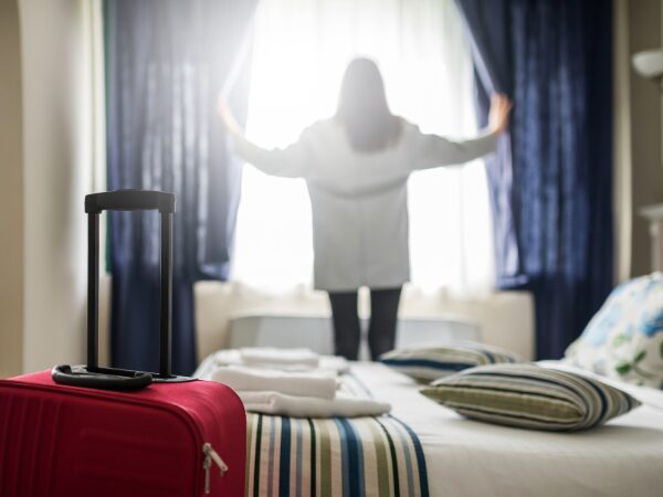 ホテルの室内でカーテンを開けて外を見る女性