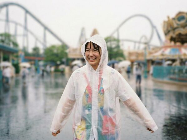 レインポンチョを着て、パーク内を笑顔で歩く女性