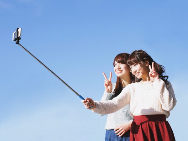 自撮り棒を使って写真を撮る女性二人