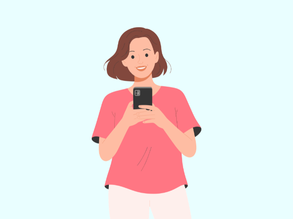 ピンク色のTシャツを着てスマホを見ながら笑顔の女性
