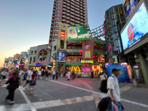ユニバーサル・スタジオ・ジャパン(USJ)に隣接するユニバーサル・シティウォーク大阪。カラフルな看板や飲食店が並び、観光客でにぎわう夕暮れの商業施設。